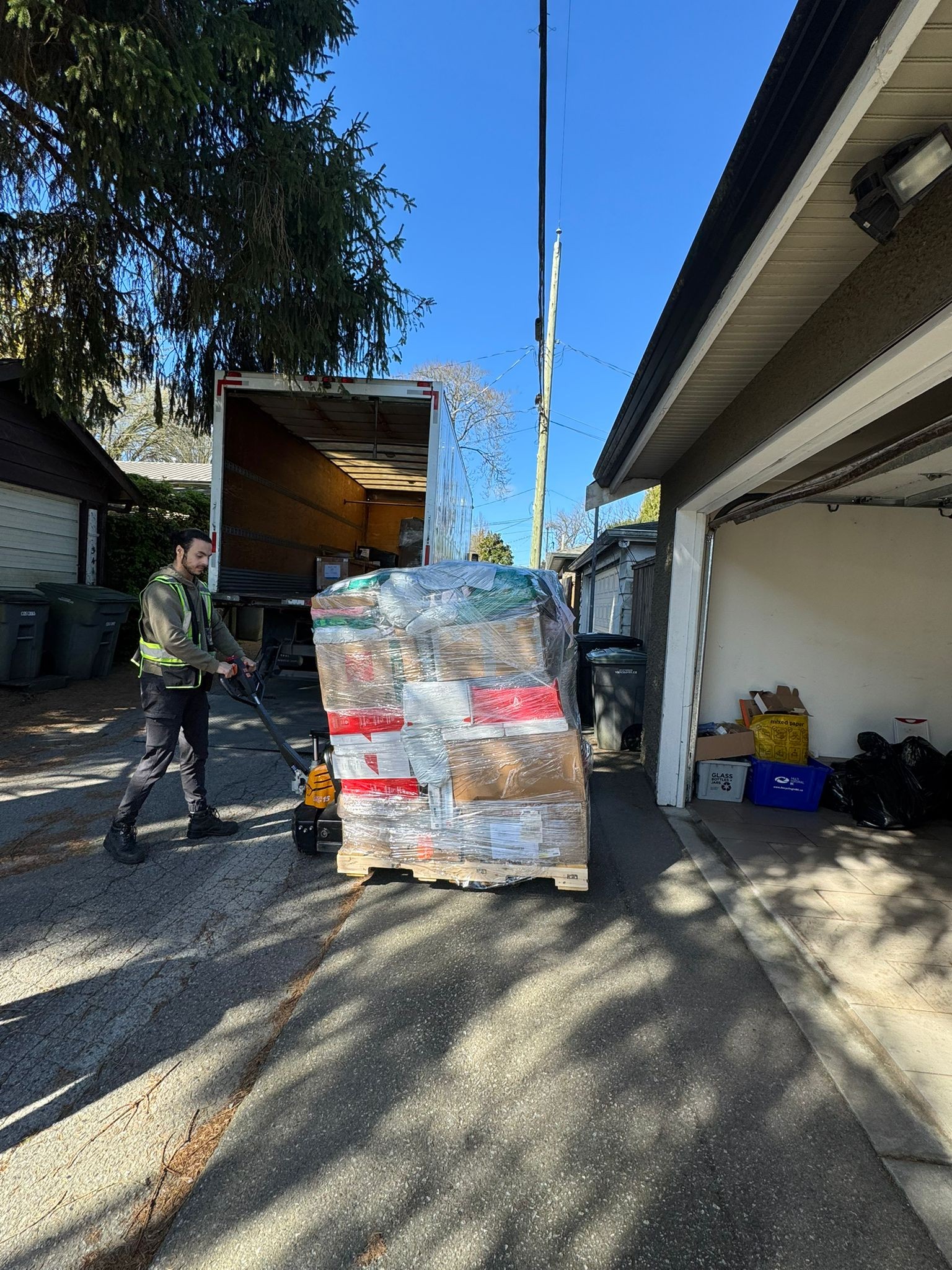 April 2026 Delivery - Worker pulling pallet toward garage with electric jack
