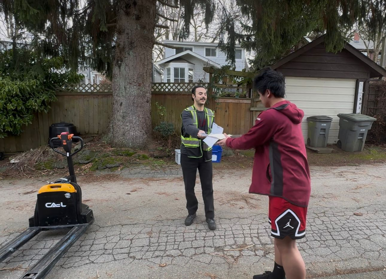 Heading into 2026 Batch - Delivery worker and R3 team coordinating paperwork in driveway