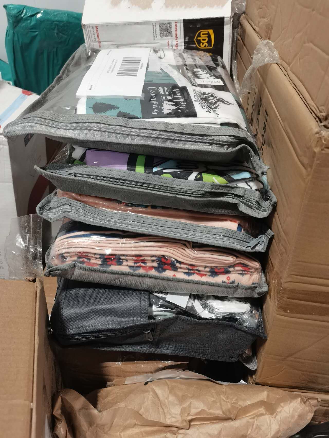 Stacked clothing items in gray packaging inside a cardboard box